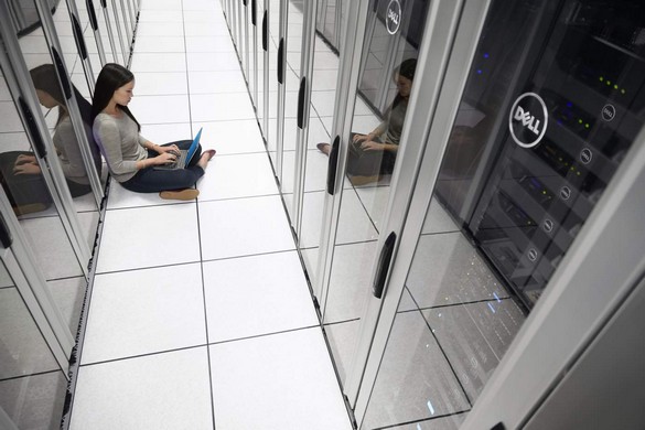 Woman Sitting in Data Center with Notebook