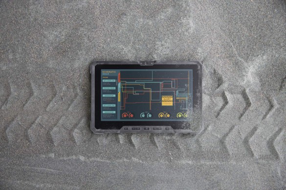 A Dell Latitude 12 Rugged Tablet computer (Model 7202) laying face-up on a gravel path with tire tracks beneath it.