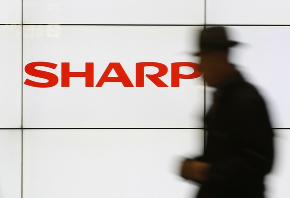 A pedestrian walks past a logo of Sharp Corp at a train station in Tokyo in this February 3, 2014 file photo. Embattled Japanese electronics maker Sharp Corp is preparing to seek aid from its two main lenders, a source with direct knowledge of the matter said, as it expects impairment losses from unprofitable businesses to mount this year. <a href=